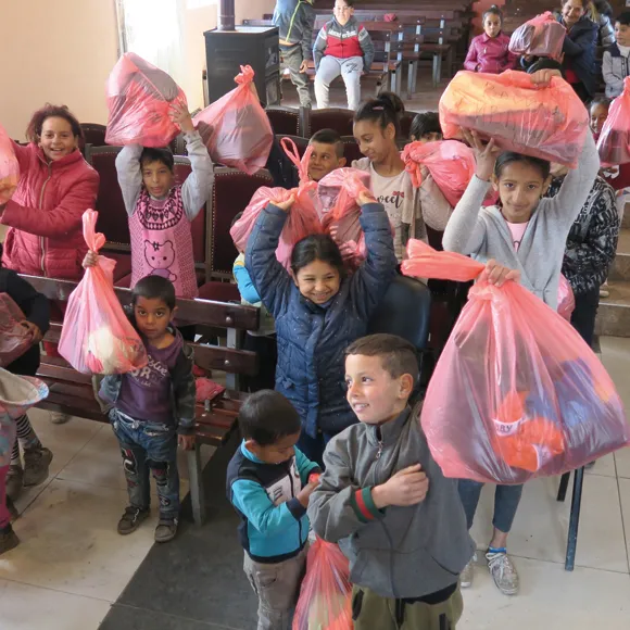 Group of happy children receiving bundles of clothes